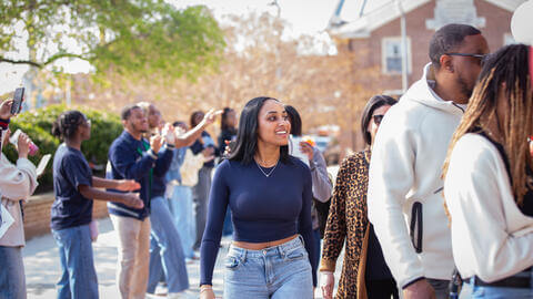Woman walking and smiling at an event on Howard's campus