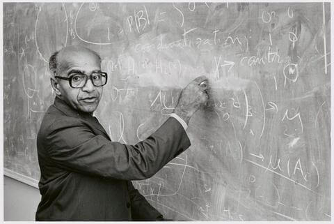 David Blackwell writing math algorithms on a blackboard in black and white image
